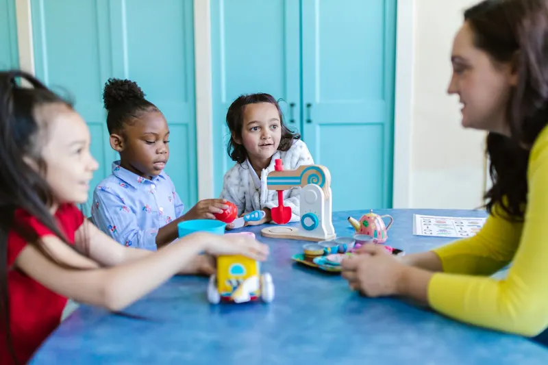 Erzieherin baut mit Kindern Bauklötze in einer Kita
